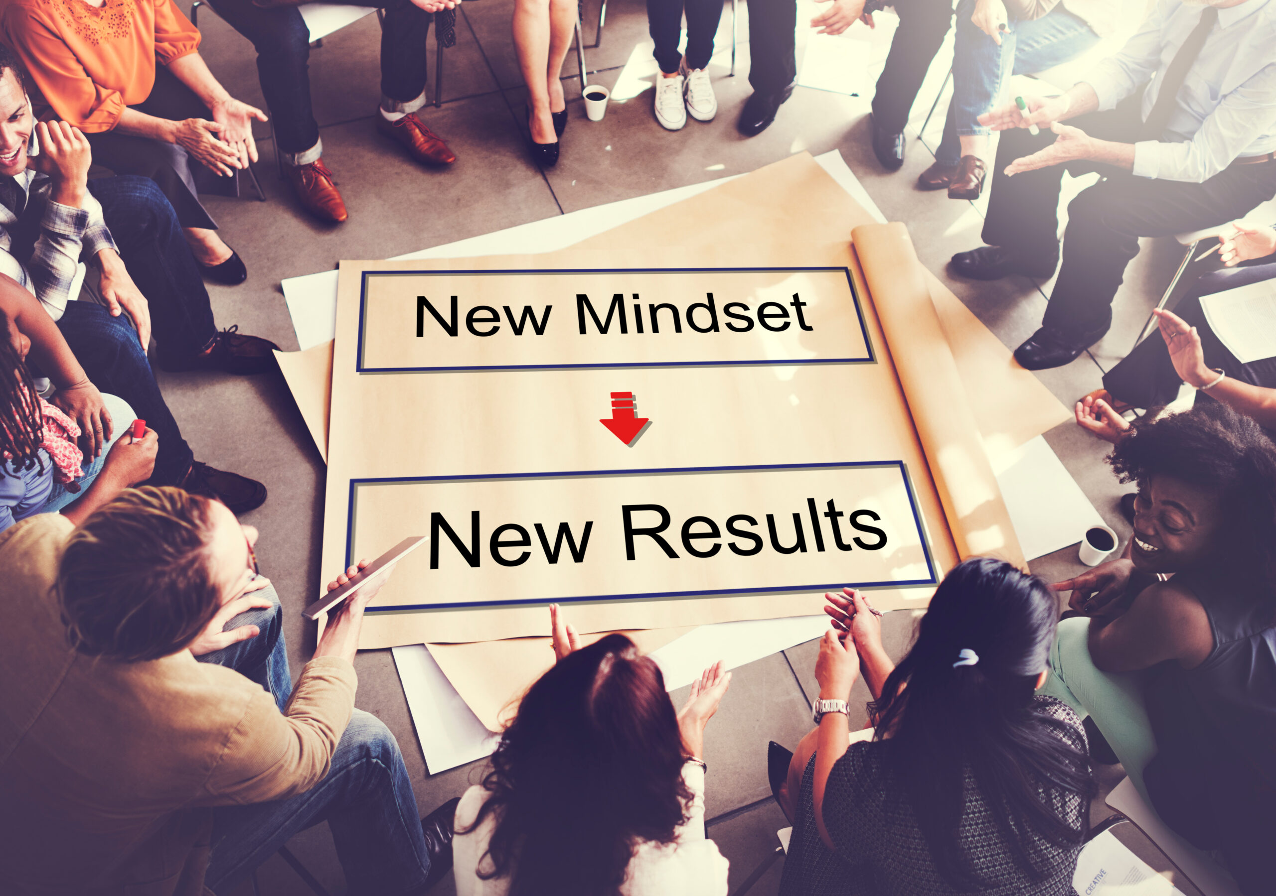 Teilnehmer in einem Workshop sitzen um ein Flip Chart zum Thema Mindset und Resultate.